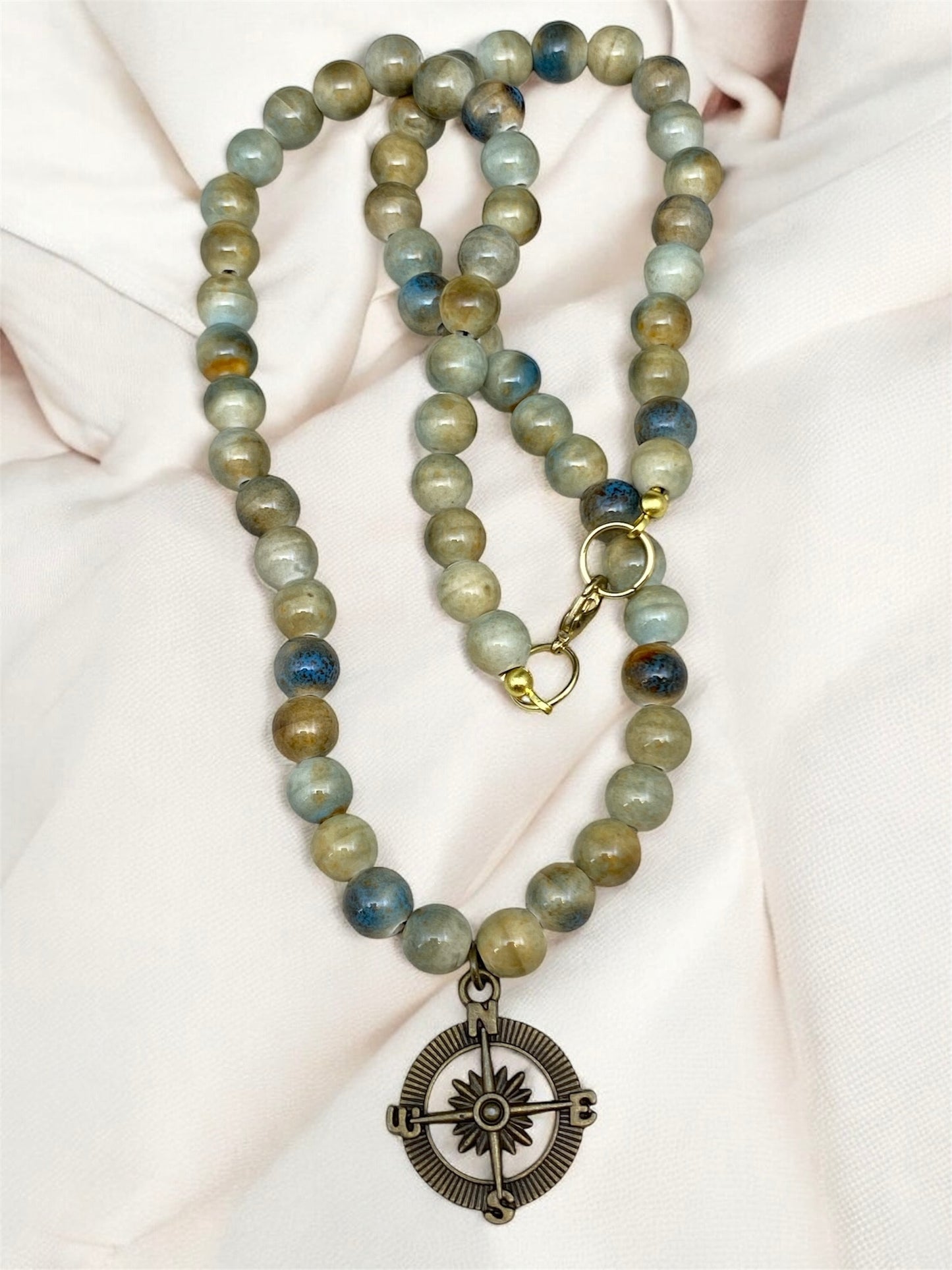 Beaded necklace with a pendant on a beige fabric background