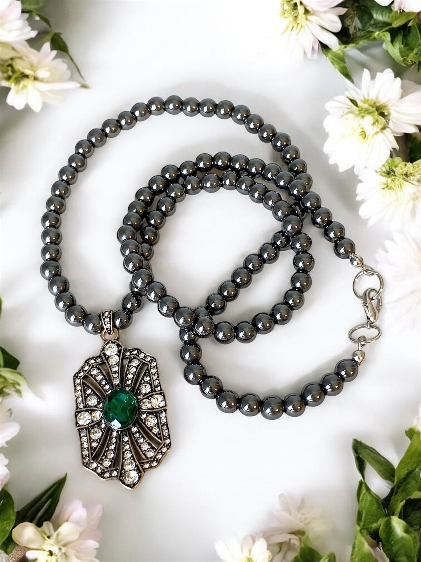 Necklace with gray beads and a decorative pendant on a floral background