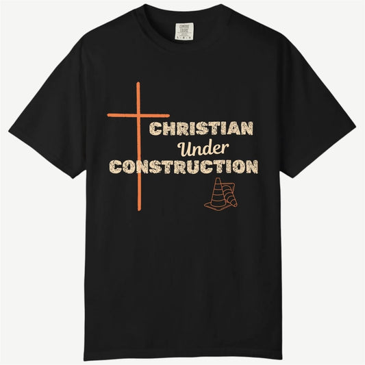 A black short-sleeve crewneck t-shirt with a graphic print on the front. The design features an orange cross, the text 'CHRISTIAN Under CONSTRUCTION' in a distressed beige font, and an orange outline of a traffic cone, all on a light beige background.