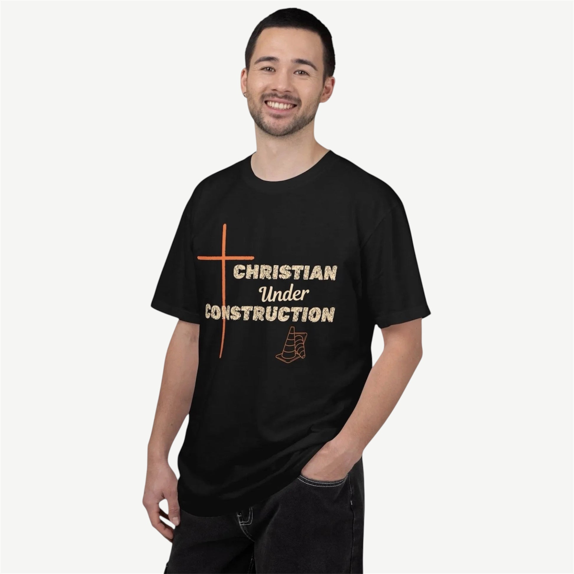A man wearing a black t-shirt with a graphic that reads 'CHRISTIAN Under CONSTRUCTION' in beige and orange, standing against a light beige background.