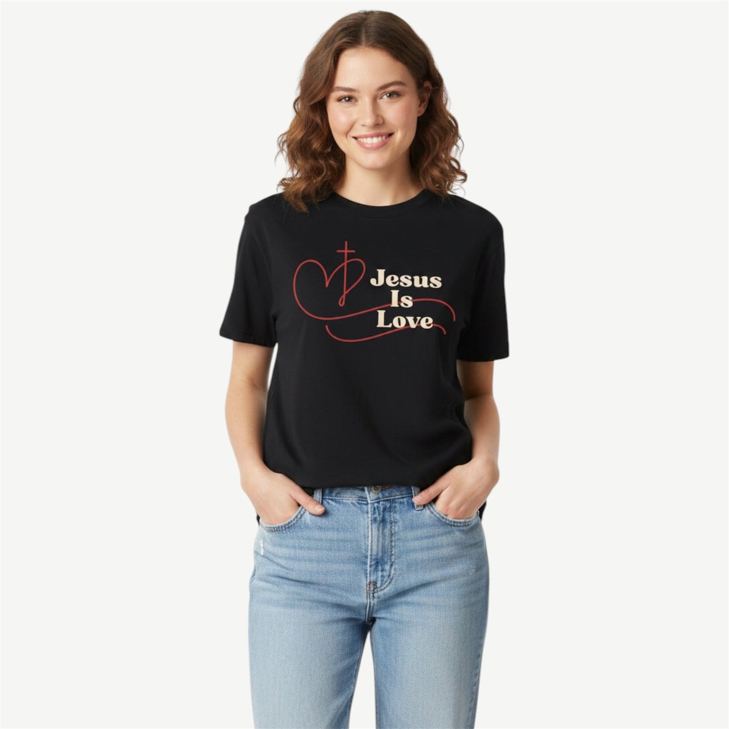 A woman wearing a black short-sleeve graphic t-shirt with the text 'Jesus Is Love' in beige, and a red heart design, paired with light blue jeans, against a light gray background.