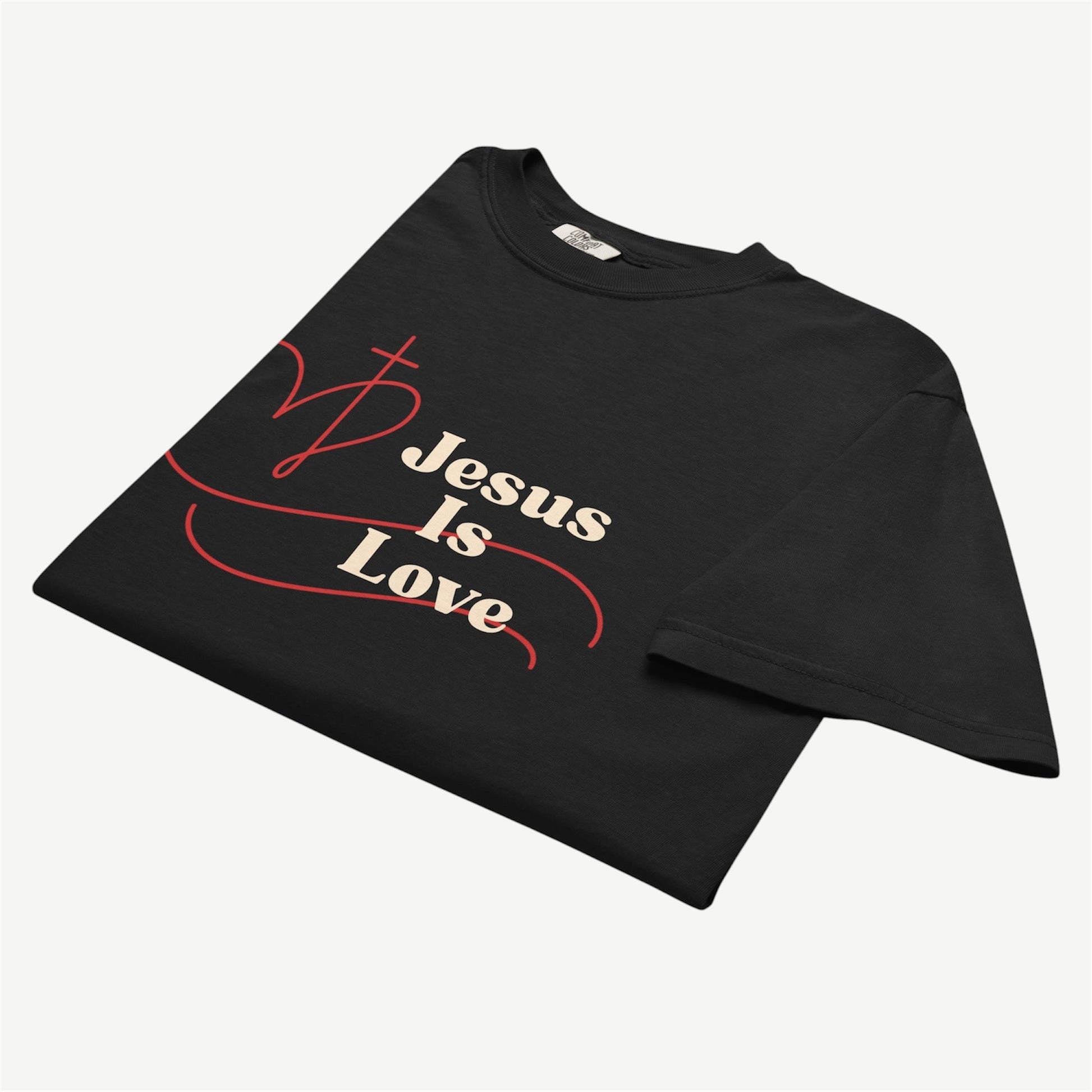 A black short-sleeve t-shirt with a graphic print on the front that reads 'Jesus Is Love' in beige text, accented by a red heart design, displayed on a light gray background.