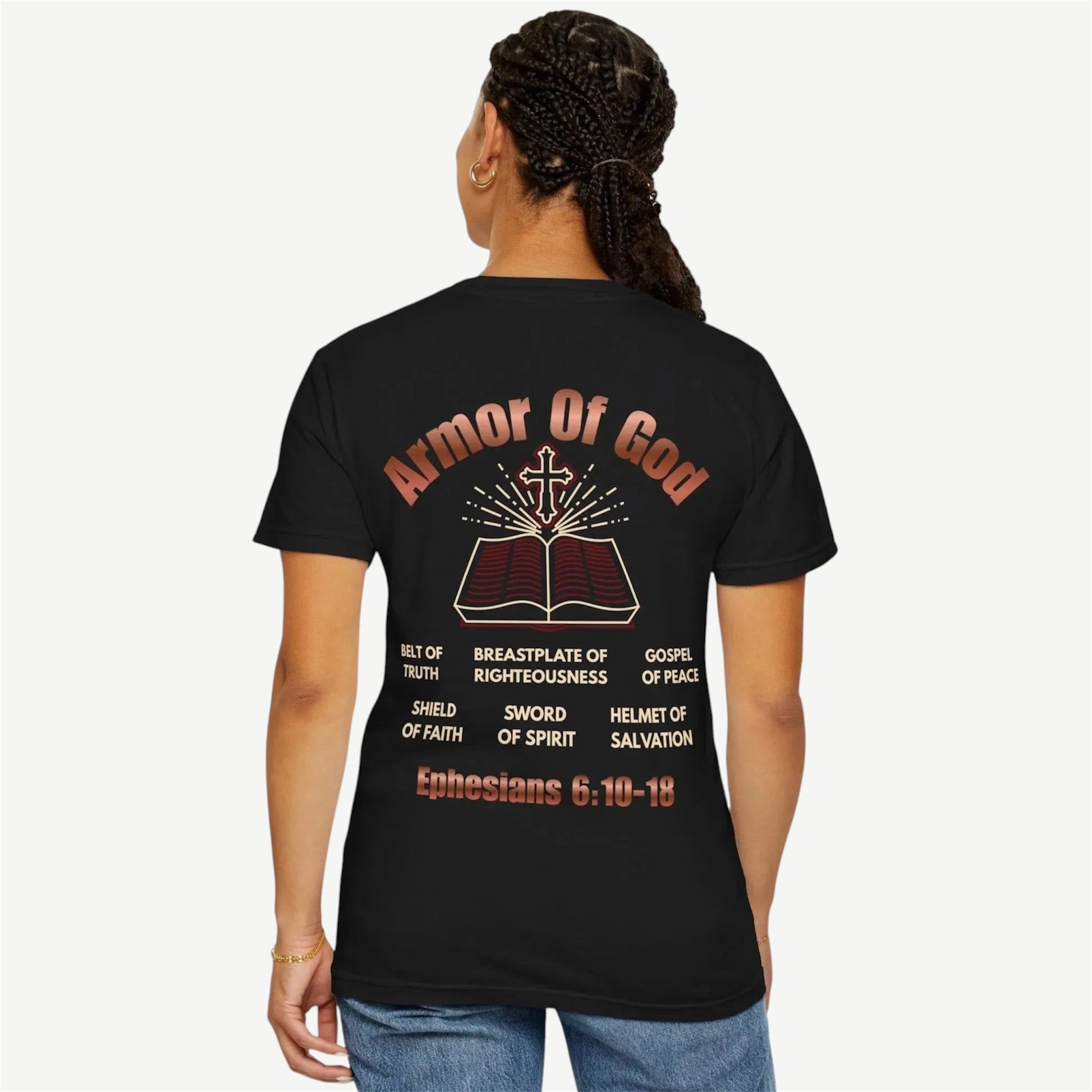 A woman shown from the back wearing a black t-shirt with a large graphic print on the back. The graphic features the text 'Armor Of God' in a reddish-brown font above an illustration of an open Bible with a cross, followed by theological terms and the scripture 'Ephesians 6:10-18' at the bottom.