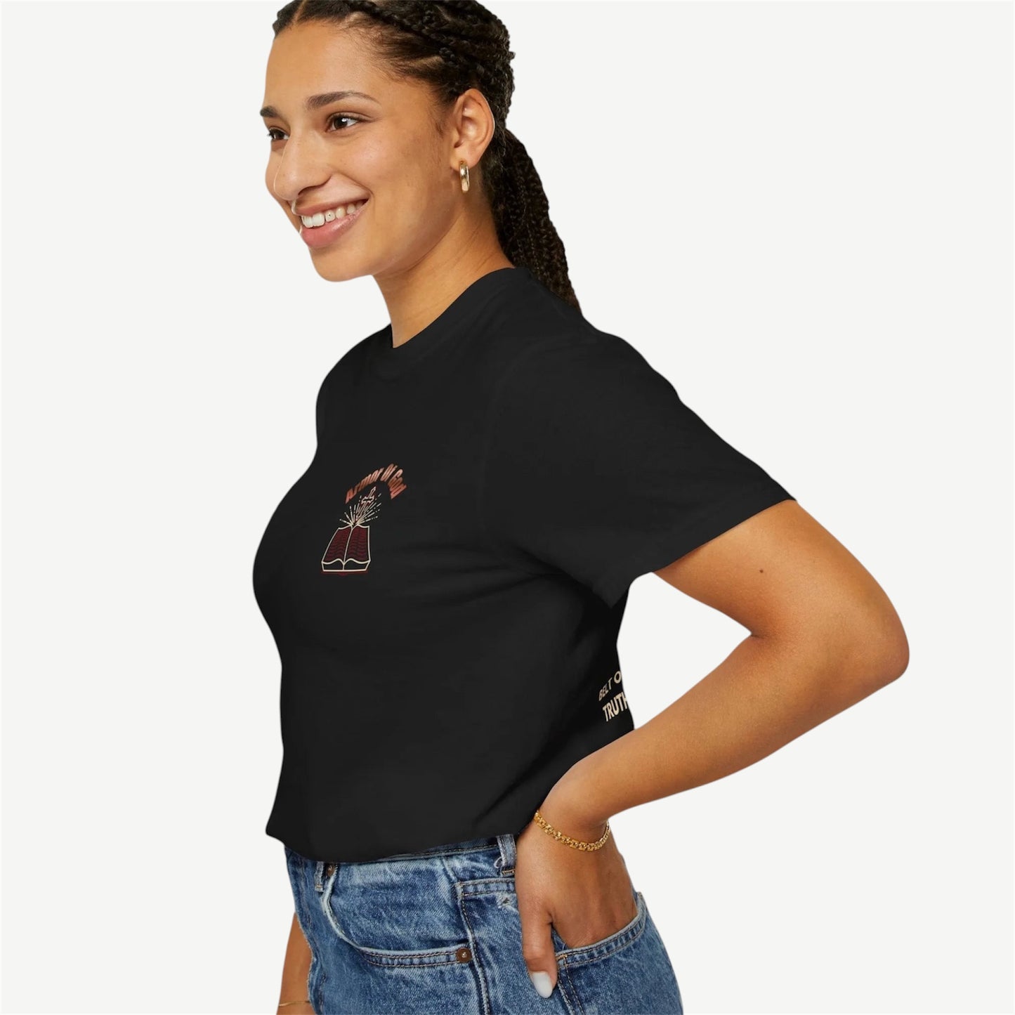 A woman wearing a black short-sleeve t-shirt with a small graphic on the left chest, paired with blue jeans, photographed against a light gray background.